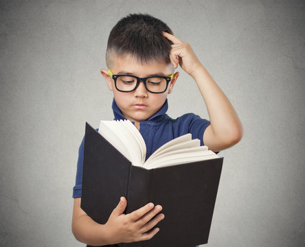 child with glasses reading book isolated grey background 