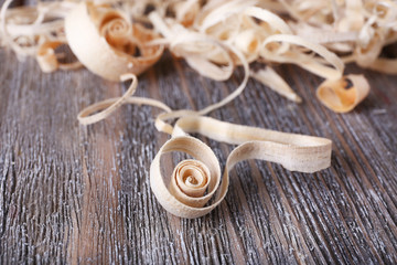 Wood shavings on grey wooden background closeup