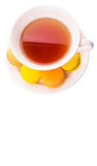 A cup of tea and yellow and orange colored macarons 