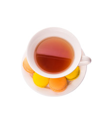 A cup of tea and yellow and orange colored macarons 