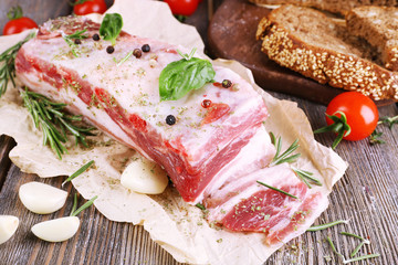 raw bacon with bread and spices on wooden table