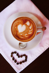 Cup of coffee with cute drawing in cafe