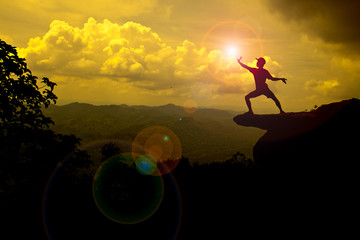 man stand on mountain trying to catch the Sun