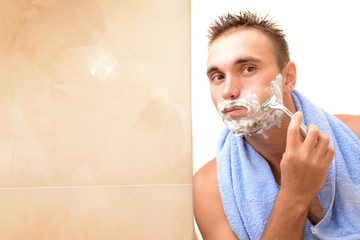 Young man shaving his beard in bathroom