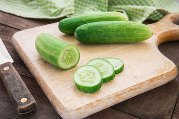 Fresh cucumber on wooden chopping board