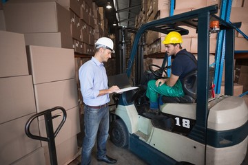 Warehouse manager talking with forklift driver