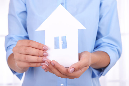 Woman hands holding paper house on light background