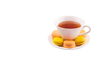 A cup of tea and yellow and orange colored macarons 