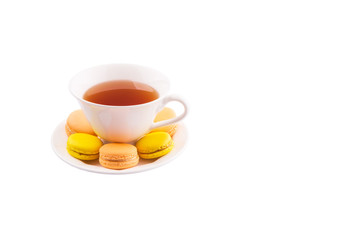 A cup of tea and yellow and orange colored macarons 