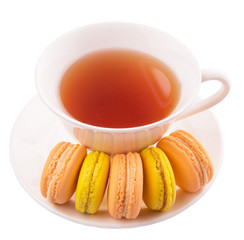 A cup of tea and yellow and orange colored macarons 