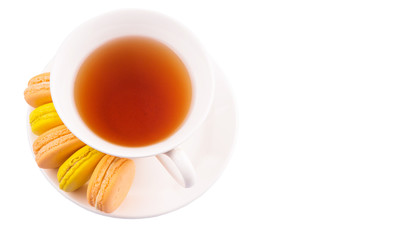 A cup of tea and yellow and orange colored macarons 