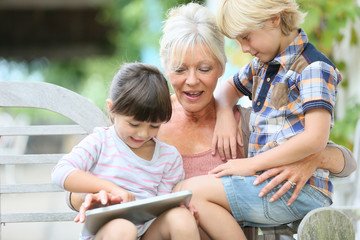 Grandmother with kids playing games on tablet