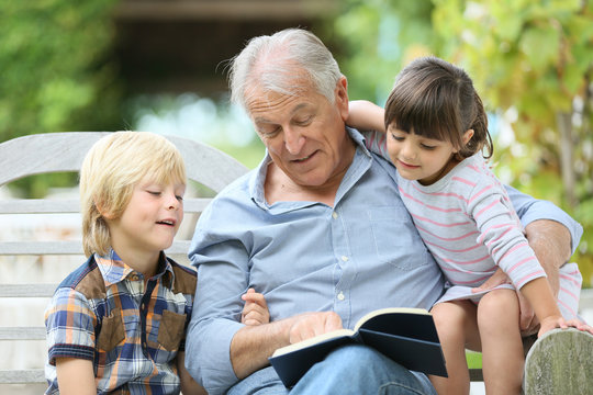 Senior man reading book with grandkids