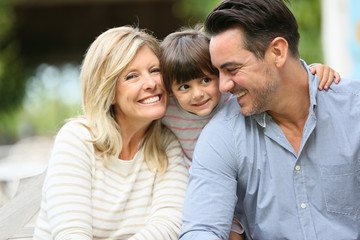 Fototapeta premium Portrait of parents with daughter sitting outside