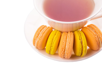 A cup of tea and yellow and orange colored macarons 