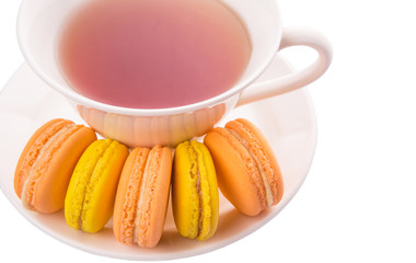 A cup of tea and yellow and orange colored macarons 