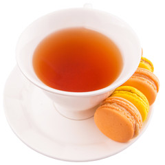 A cup of tea and yellow and orange colored macarons 