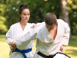 Young woman and man practicing karate outdoors