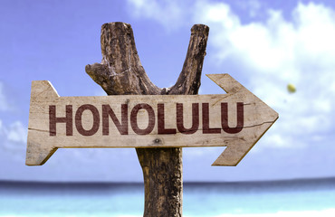 Honolulu wooden sign with a beach on background