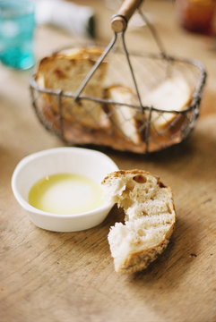 Bread slices in a basket, one half eaten slice and a dish of oil.