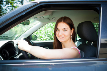 Beautiful young woman/girl/teenager driving her first new car after car school/obtain driving licence (colorful image, shallow DOF)