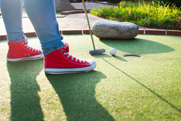 Young woman plays adventure/mini golf in summer evening