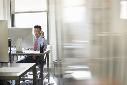 A man seated at a computer screen working on his own.