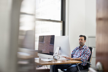 A man working in an office at a desk using a computer.