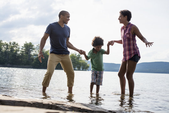 A family, parents and son spending time together by a lake in summer.