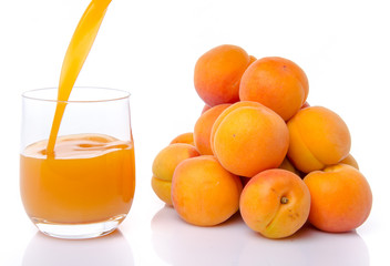 Apricot juice poured into a glass near a heap of apricots
