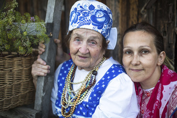 Two rural women in ethnic clothes - old and younger, outdoors.