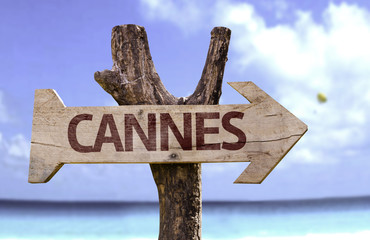 Cannes wooden sign with a beach on background