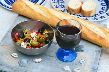 Fototapeten Een schaaltje olijven met stokbrood en rode wijn. © trinetuzun
