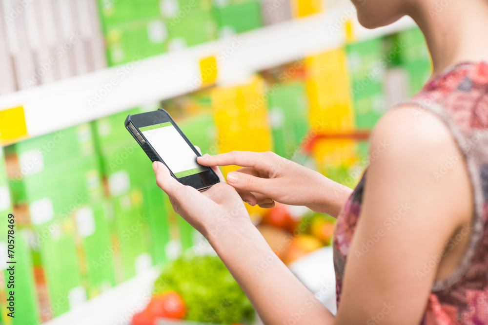 Wall mural Woman with mobile at supermarket