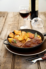 Beef steak in a pan with baked potatoes and red wine