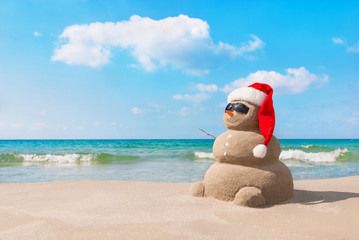 Fototapeta na wymiar Christmas snowman in santa hat at sandy beach