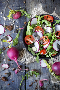 rocket salad on bowl with radish, tomatoes and seed