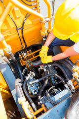 Asian mechanic repairing construction vehicle