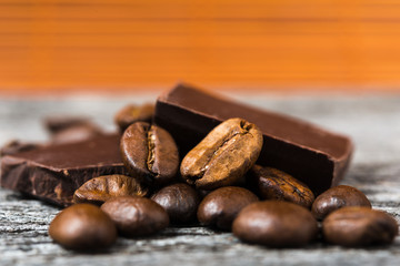 close up of coffee beans and  chocolate on brown background