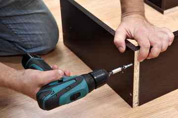 Woodworker Assembling Furniture made of chipboard using a cordle