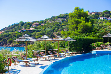 Wooden deck chairs and umbrellas near infinity pool in luxury
