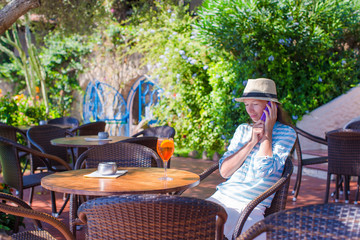 Young woman with cocktail in oitdoor cafe at exotic resort