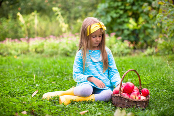 Obraz na płótnie Canvas Little girl with basket of apples in sunny autumn day