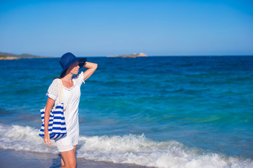 Beautiful woman in hat and bag at white sand tropical beach