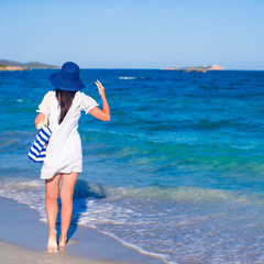 Young woman with blue stripy bag and straw hat at tropical beach