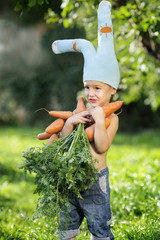 funny boy in bunny costume and an armful of fresh carrots