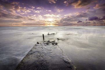 lonely destroyed pier extending deep into the ocean at sunset