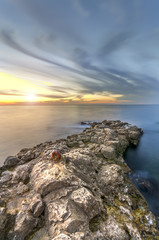 stone natural pier and smeared across the sky clouds at sunset
