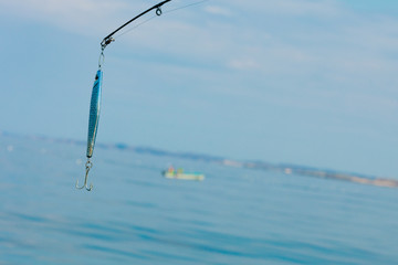 saltwater fishing - rod with wobbler and blue sea water
