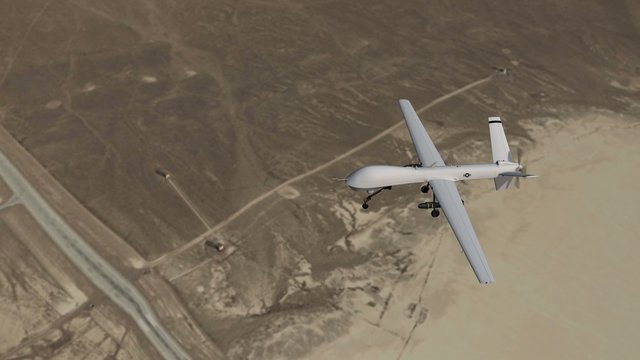 an armed drone in flight over desert - close up